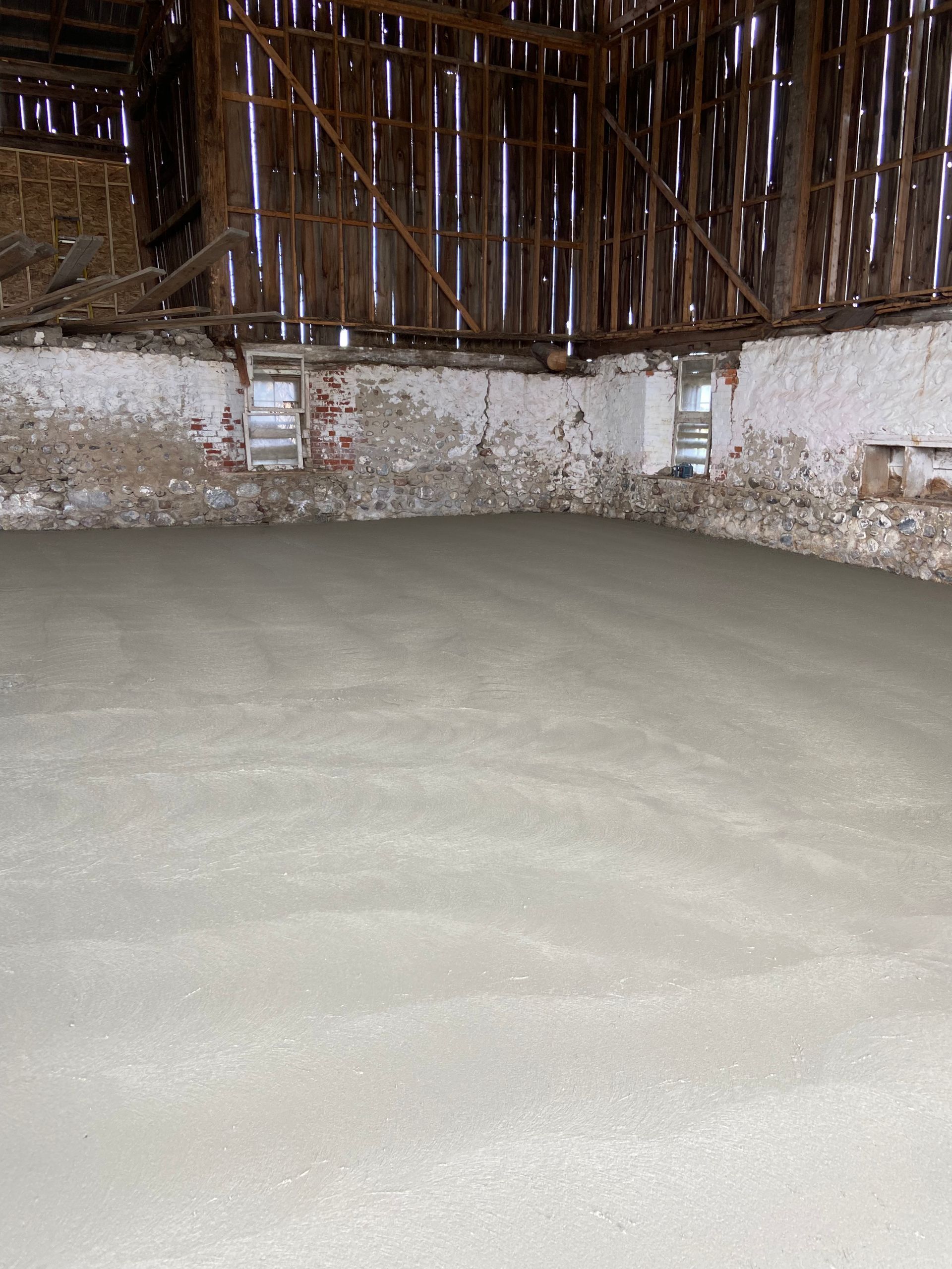 A barn with a concrete floor and a brick wall.