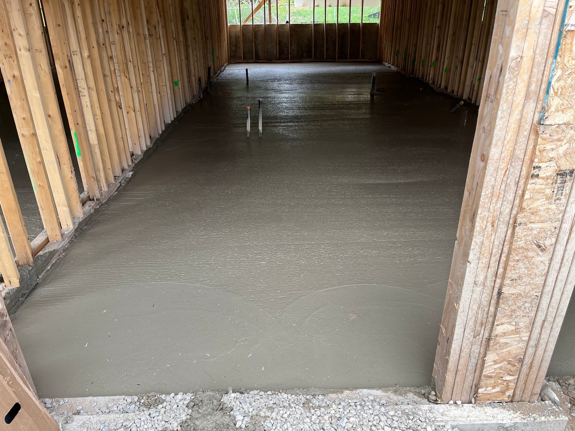 A concrete floor is being poured in a garage under construction.