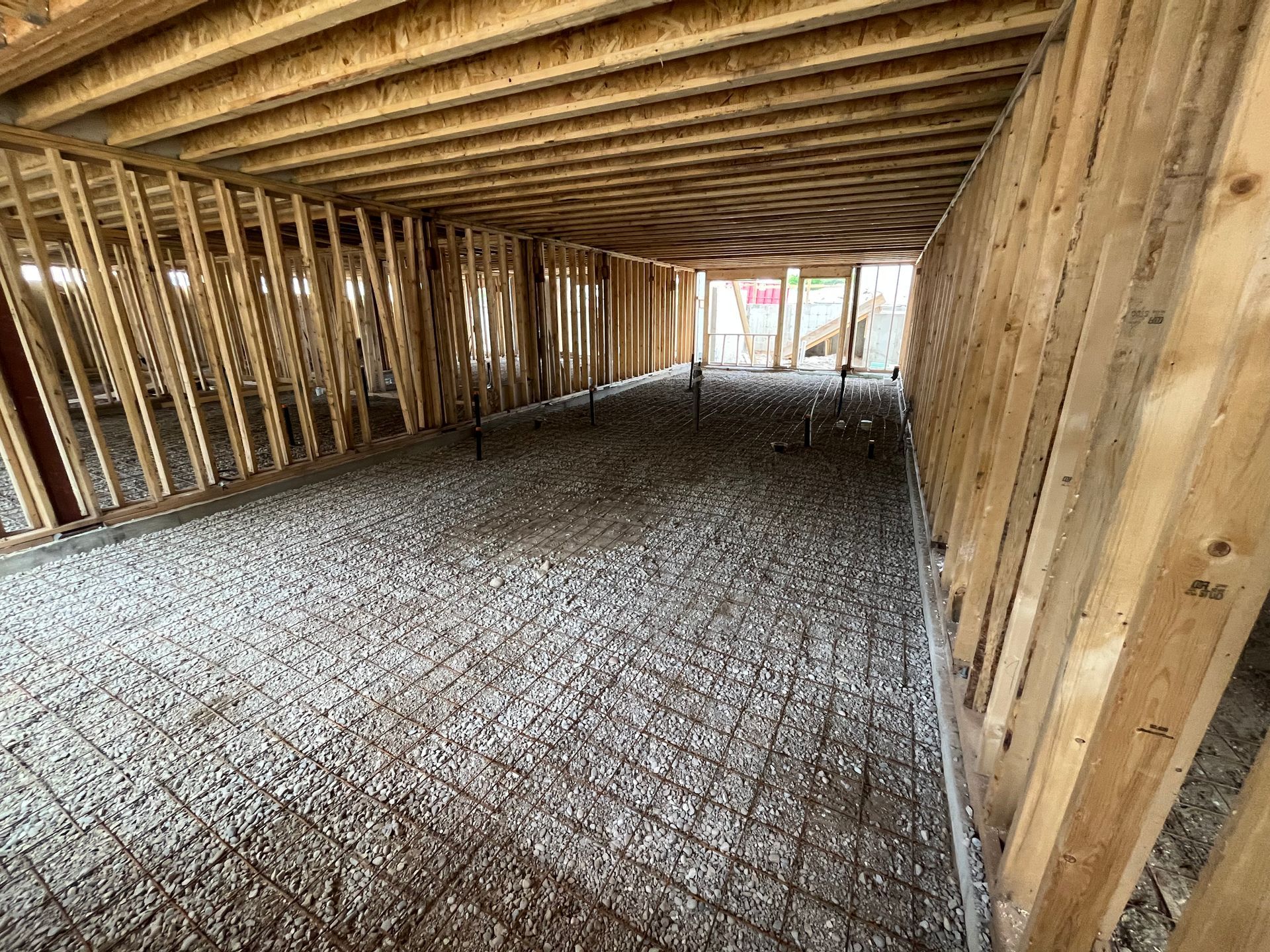 A building under construction with a lot of wooden beams and gravel on the floor.