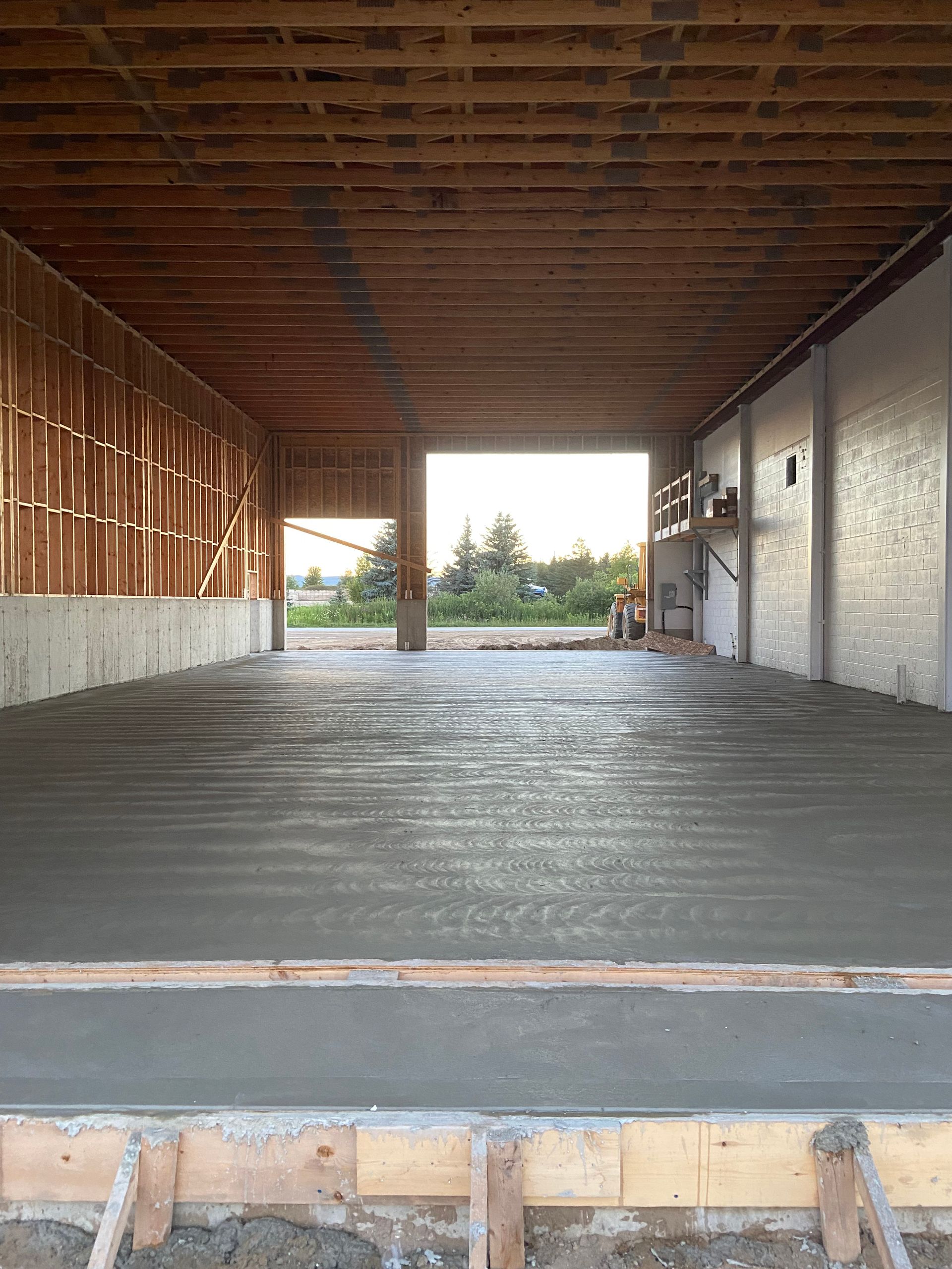 The inside of a building with a concrete floor and a wooden ceiling.