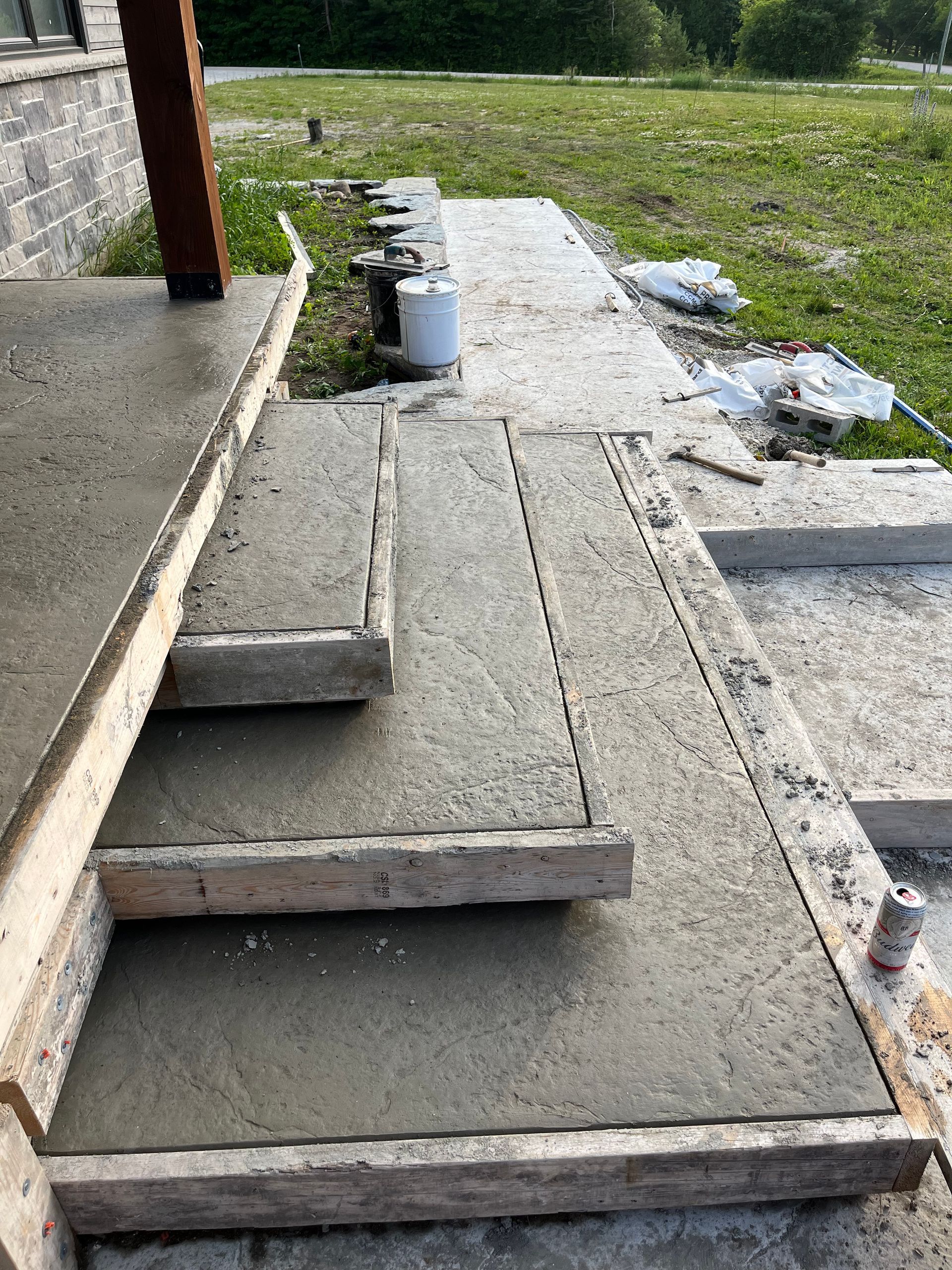 A concrete walkway is being built on the side of a house.