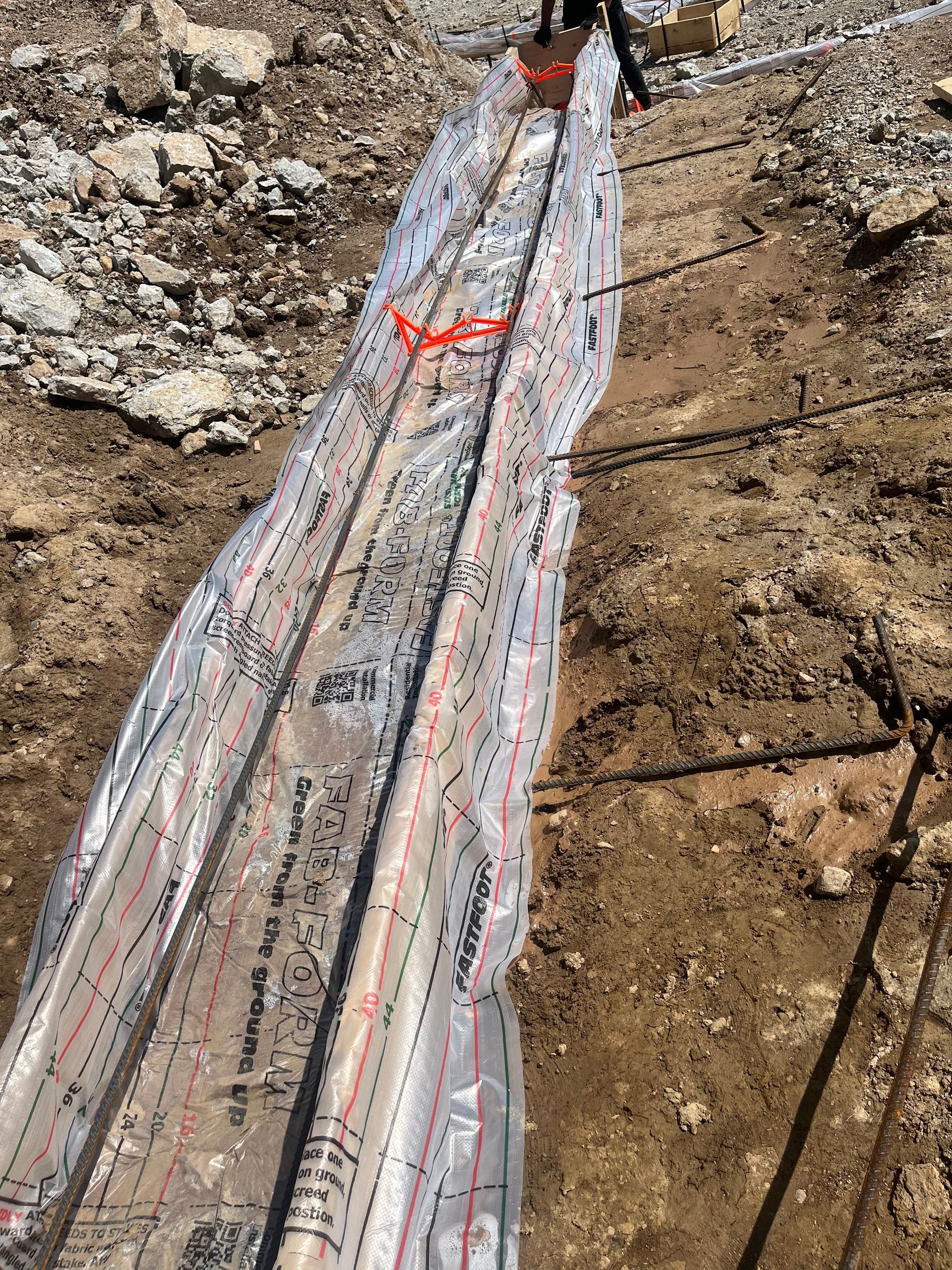 A large piece of wood is wrapped in plastic and laying on the ground.