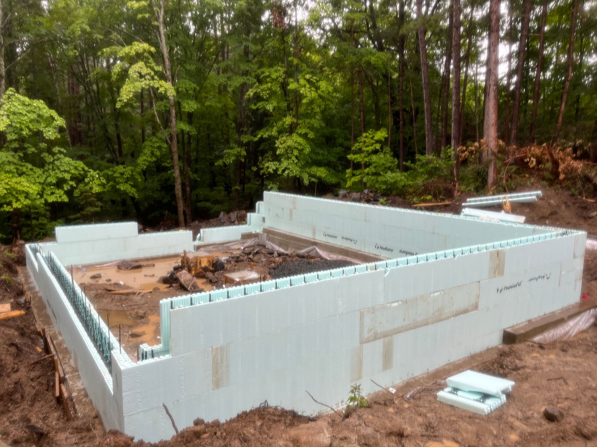 A large foundation is being built in the middle of a forest.