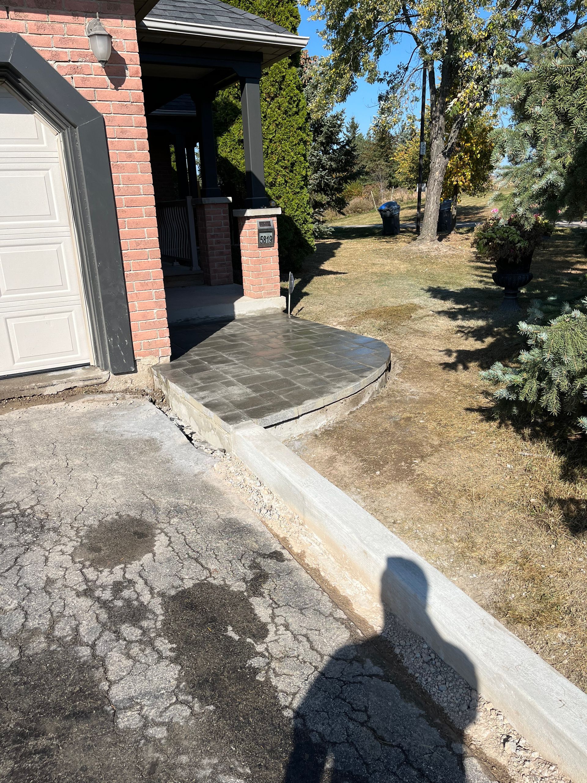 A shadow of a person is cast on the sidewalk in front of a house.