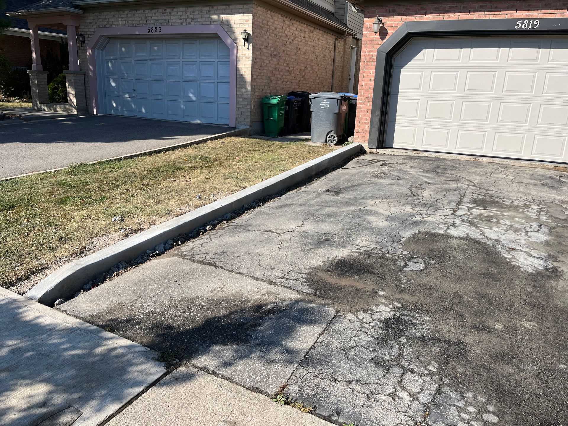 A driveway with a curb and a garage next to a house.