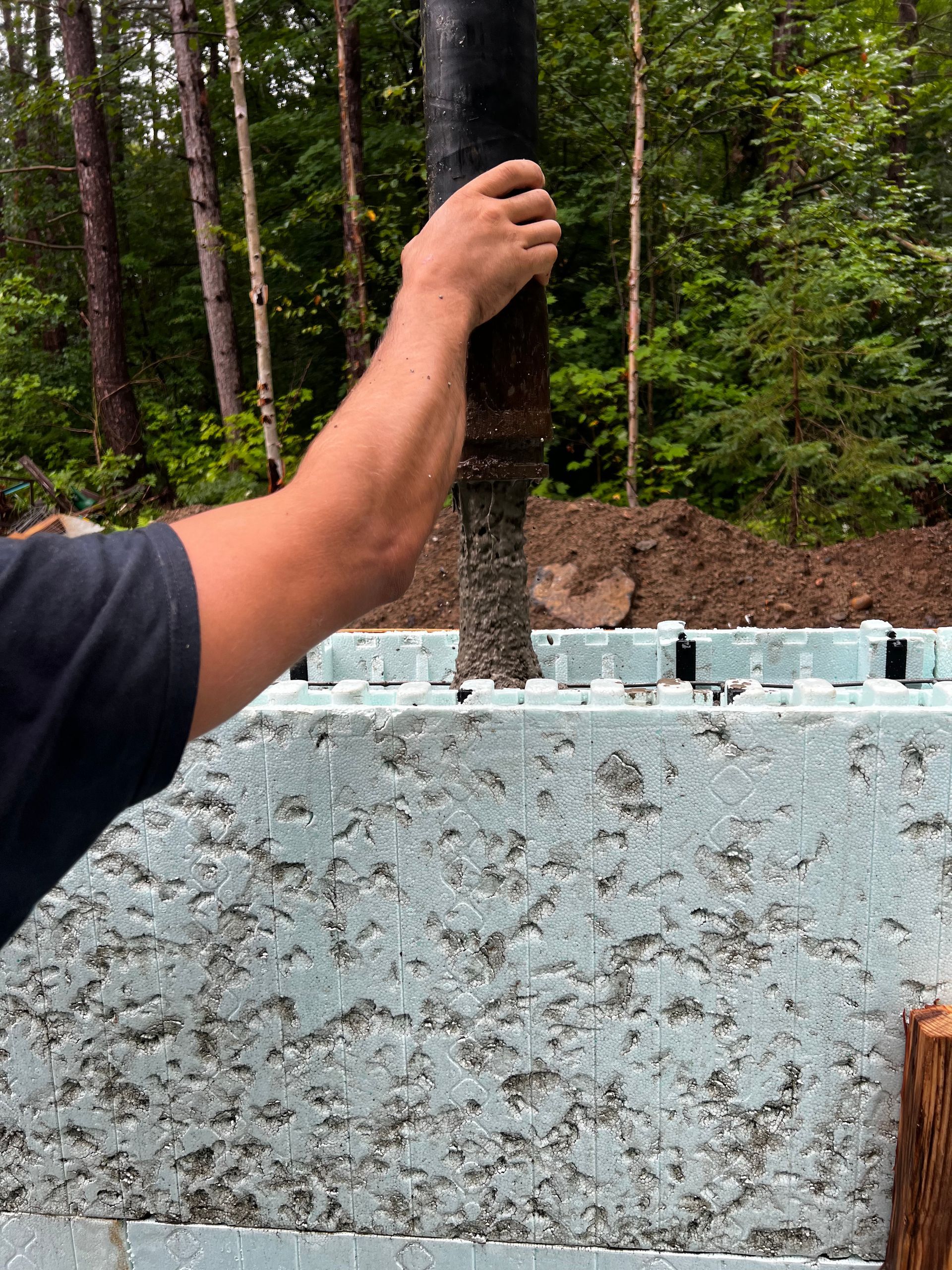 A man is pouring concrete into a foundation.