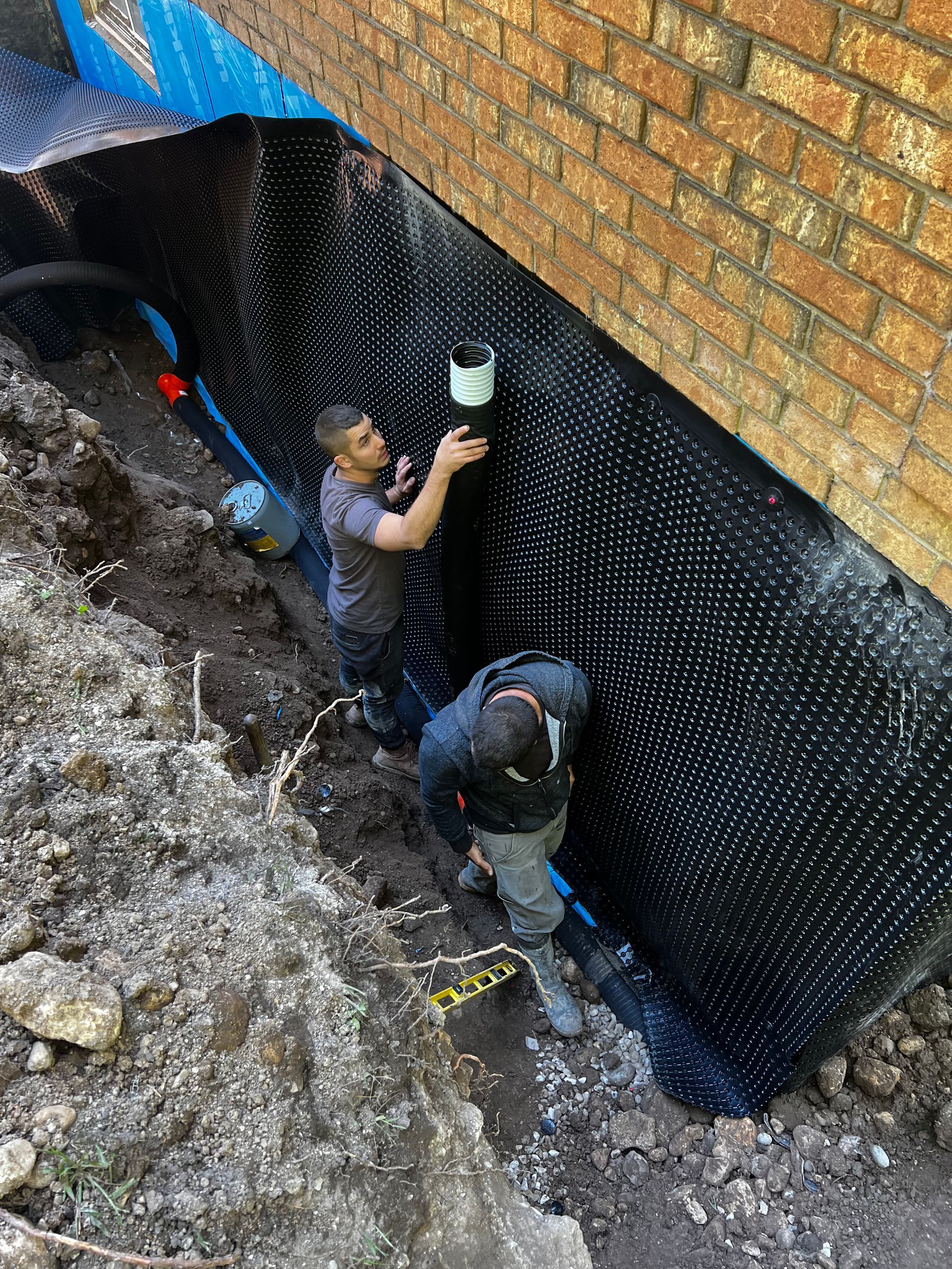 Two men are working on the foundation of a brick building.