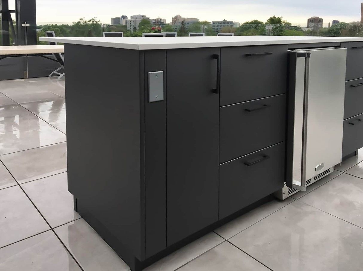 A kitchen with black cabinets and a stainless steel refrigerator