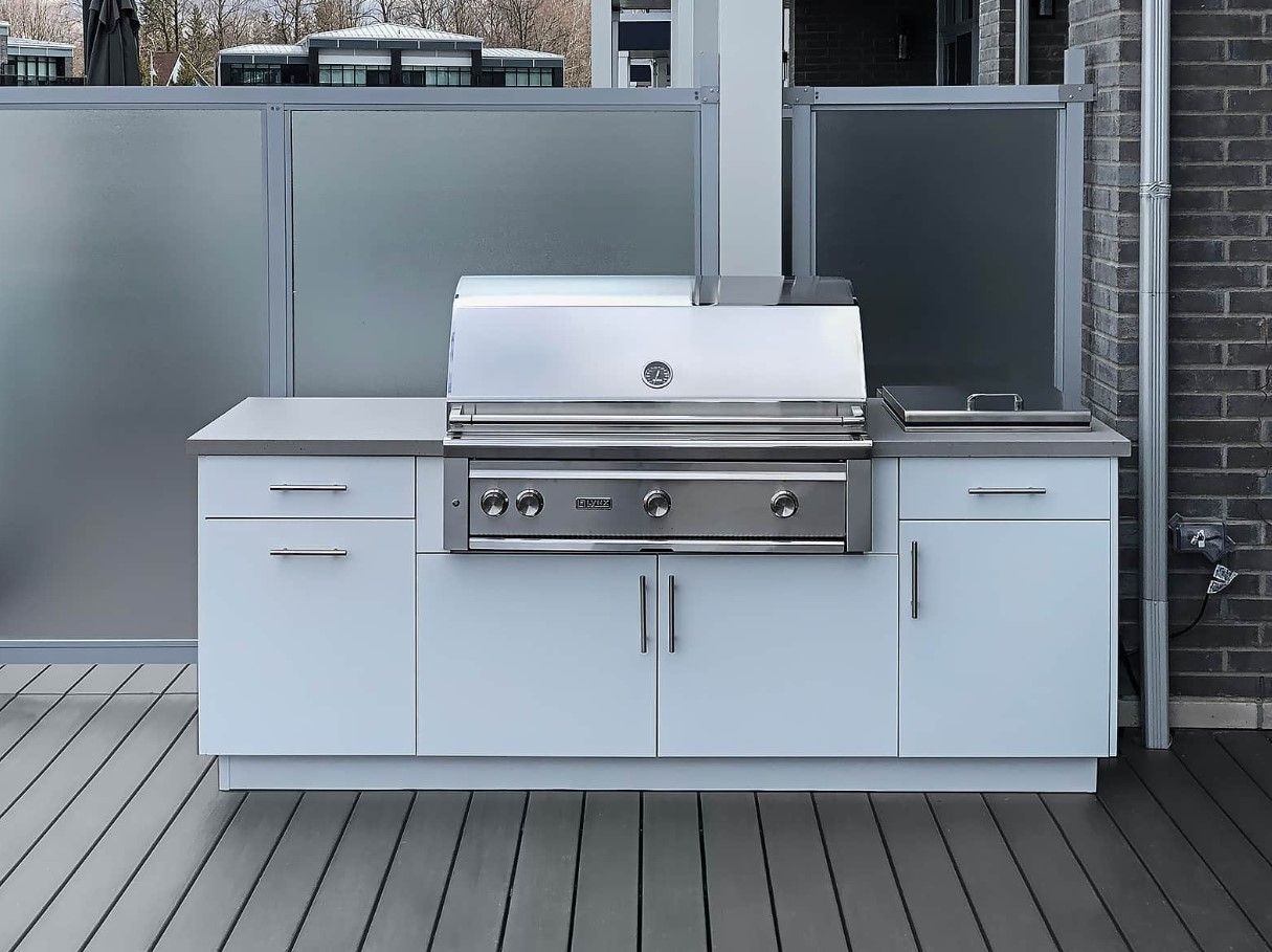 A stainless steel grill is sitting on top of a white cabinet