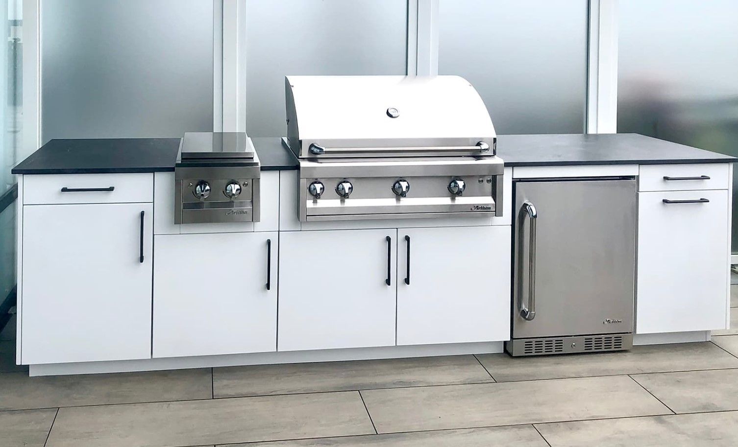 A kitchen with white cabinets and a stainless steel grill