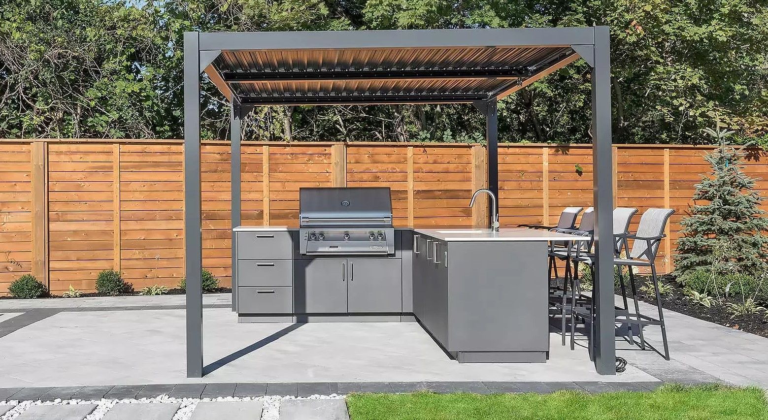 A patio with a grill and a pergola in the backyard.