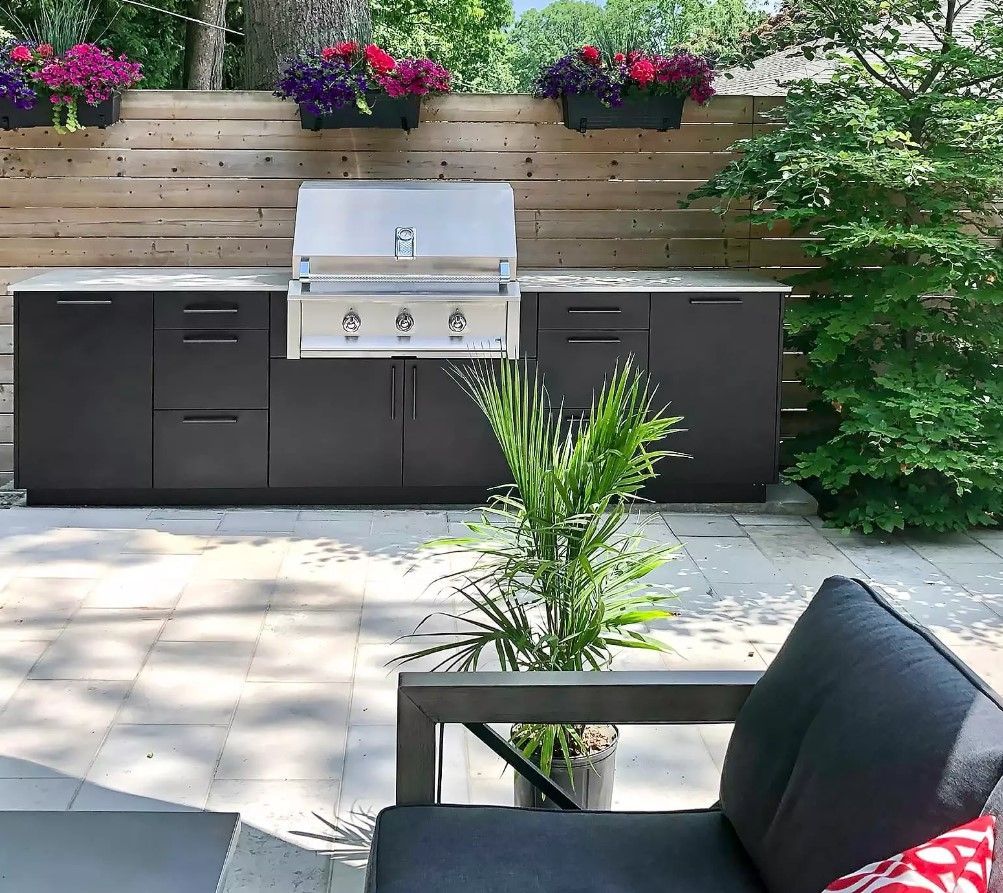 An outdoor kitchen with black cabinets and a grill