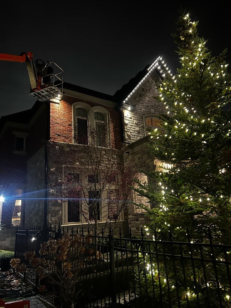 A man in a crane is decorating a house with christmas lights.