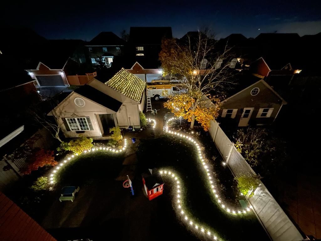 An aerial view of a backyard decorated with christmas lights at night