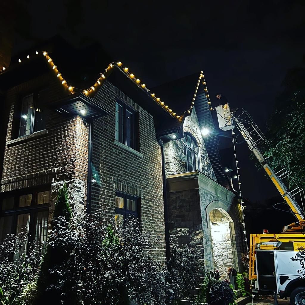 A brick house is being decorated with christmas lights at night.