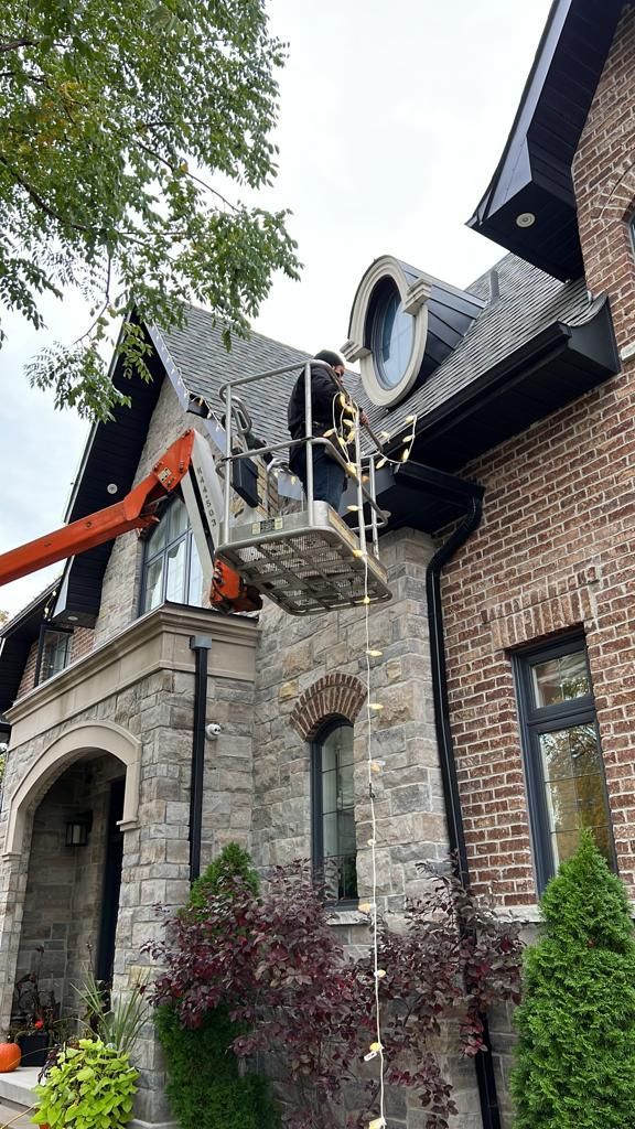 A man is working on the roof of a large brick house.