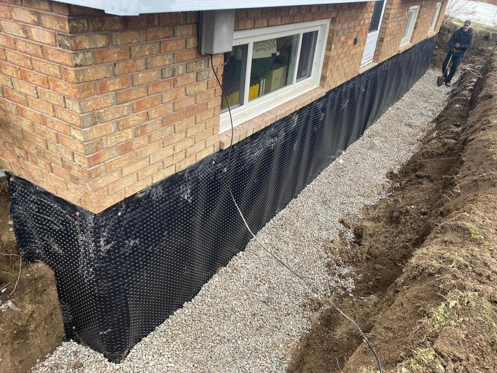 A man is digging a hole in front of a brick house.