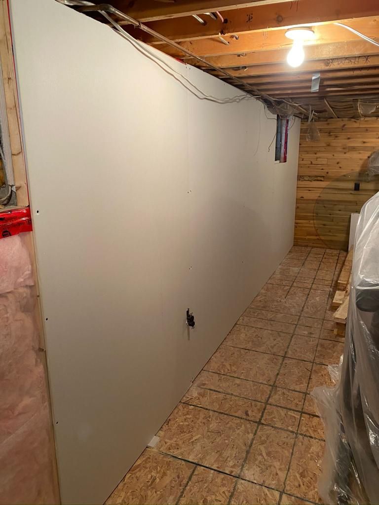 A basement with a large white wall and tile floor.