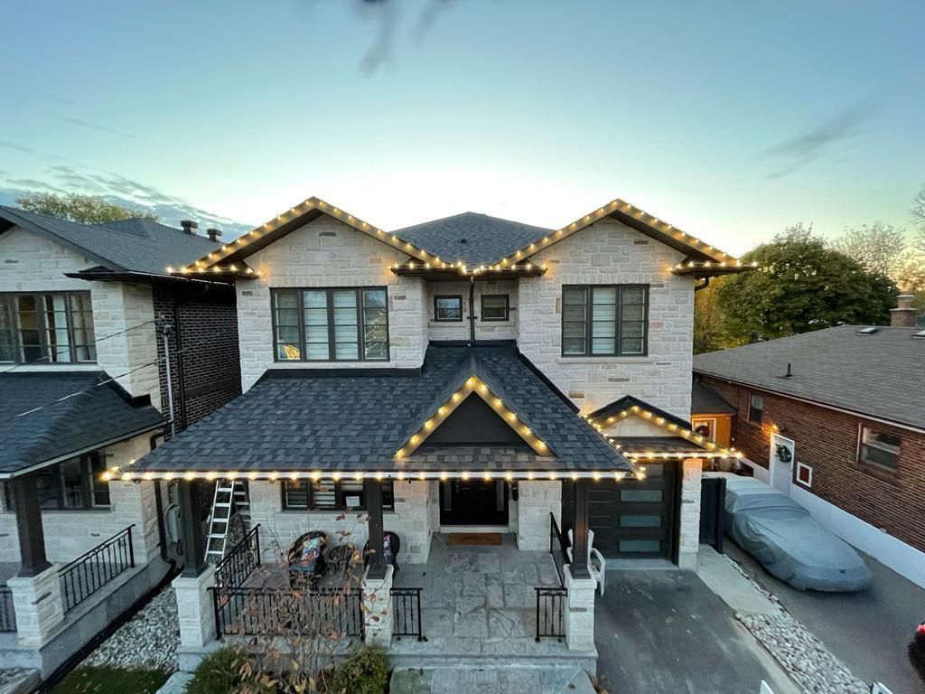 An aerial view of a large house with christmas lights on the roof.