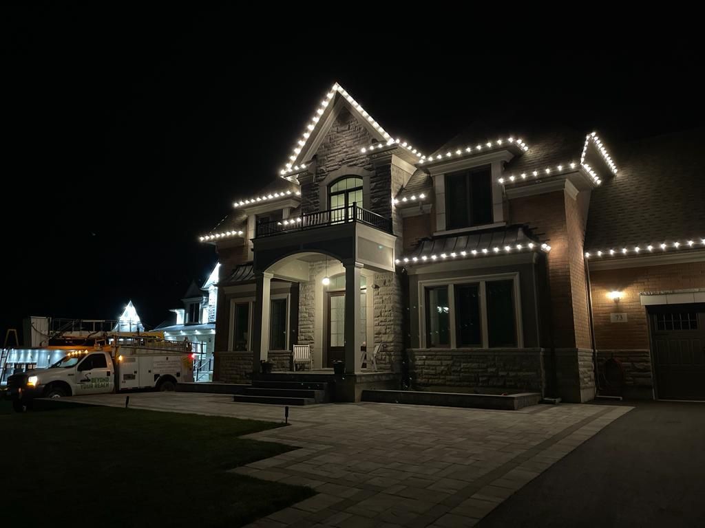 A large house is lit up at night with a truck parked in front of it.