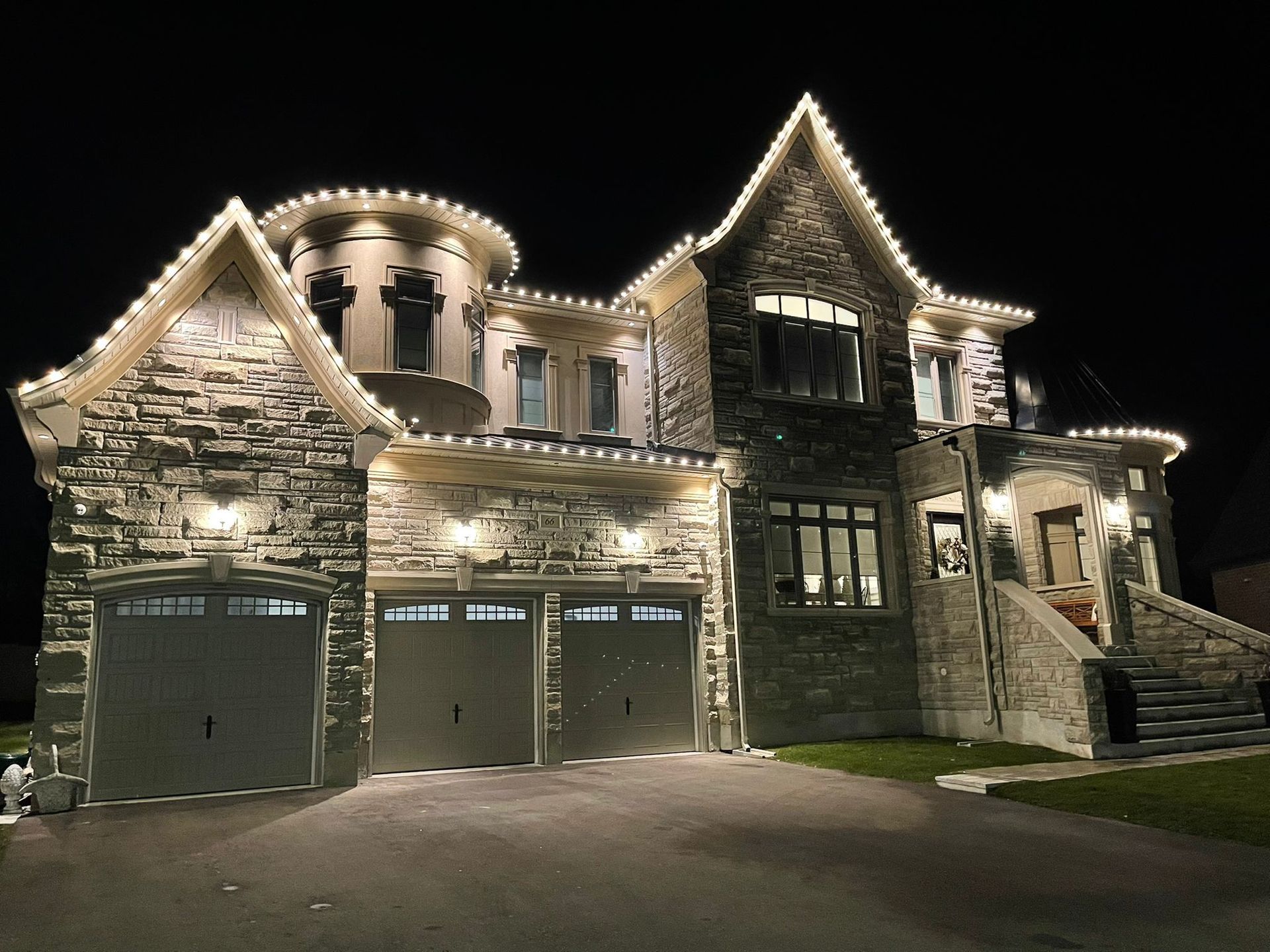 A large house is lit up at night with christmas lights.