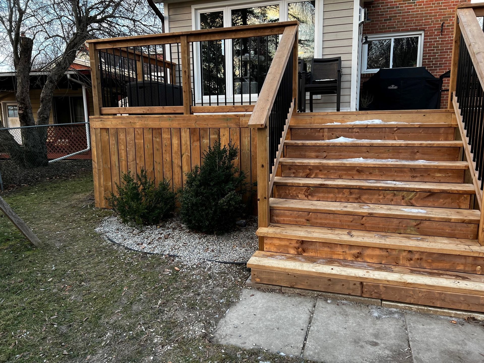 A wooden deck with stairs leading up to it in front of a house.