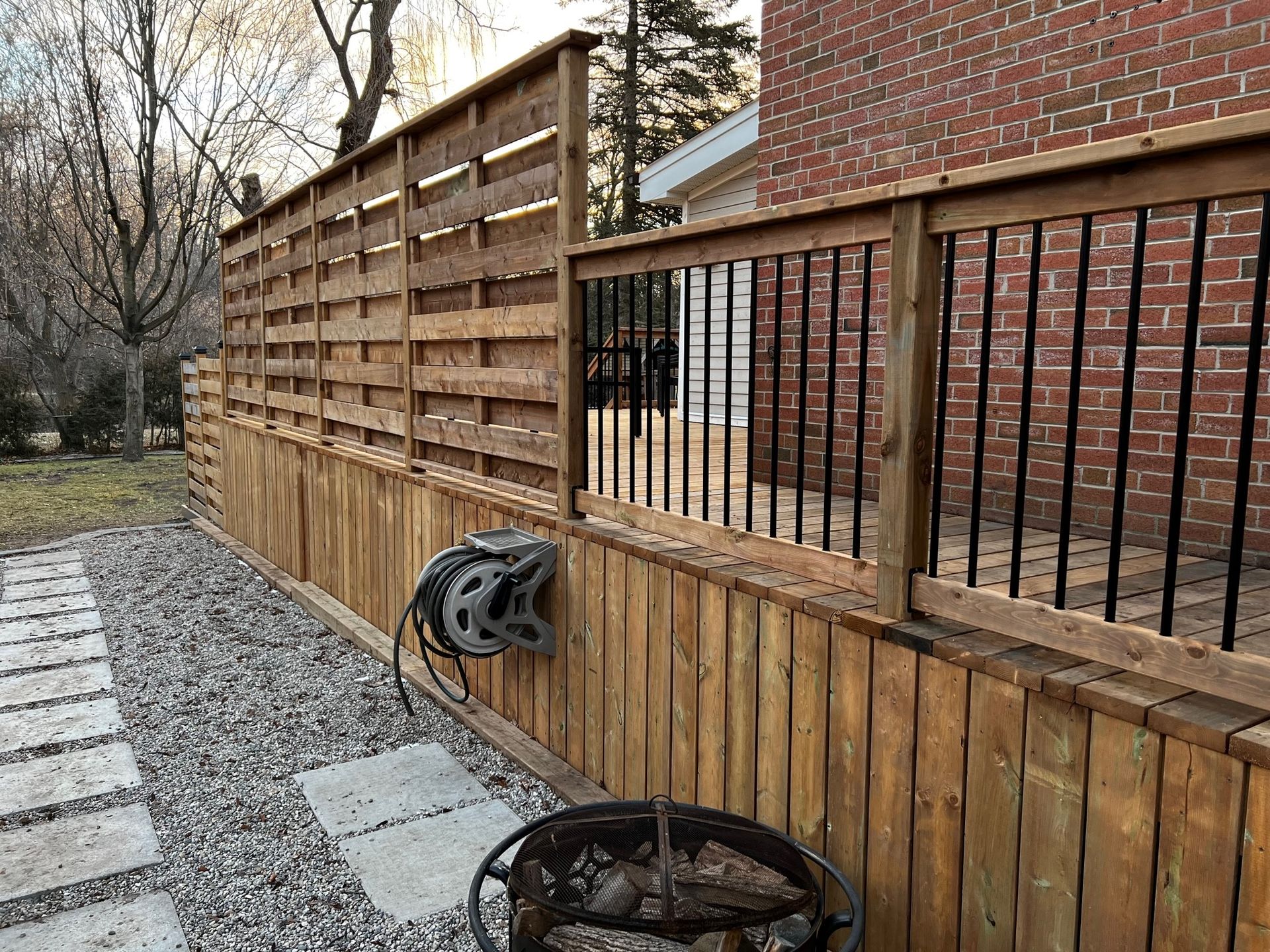 A wooden fence with a fire pit and a helmet hanging on it.