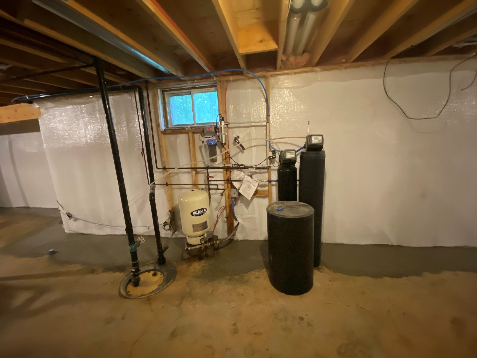 A basement with a water heater and a window.