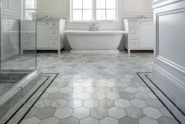 There is a bathtub in the bathroom with a hexagonal tile floor.