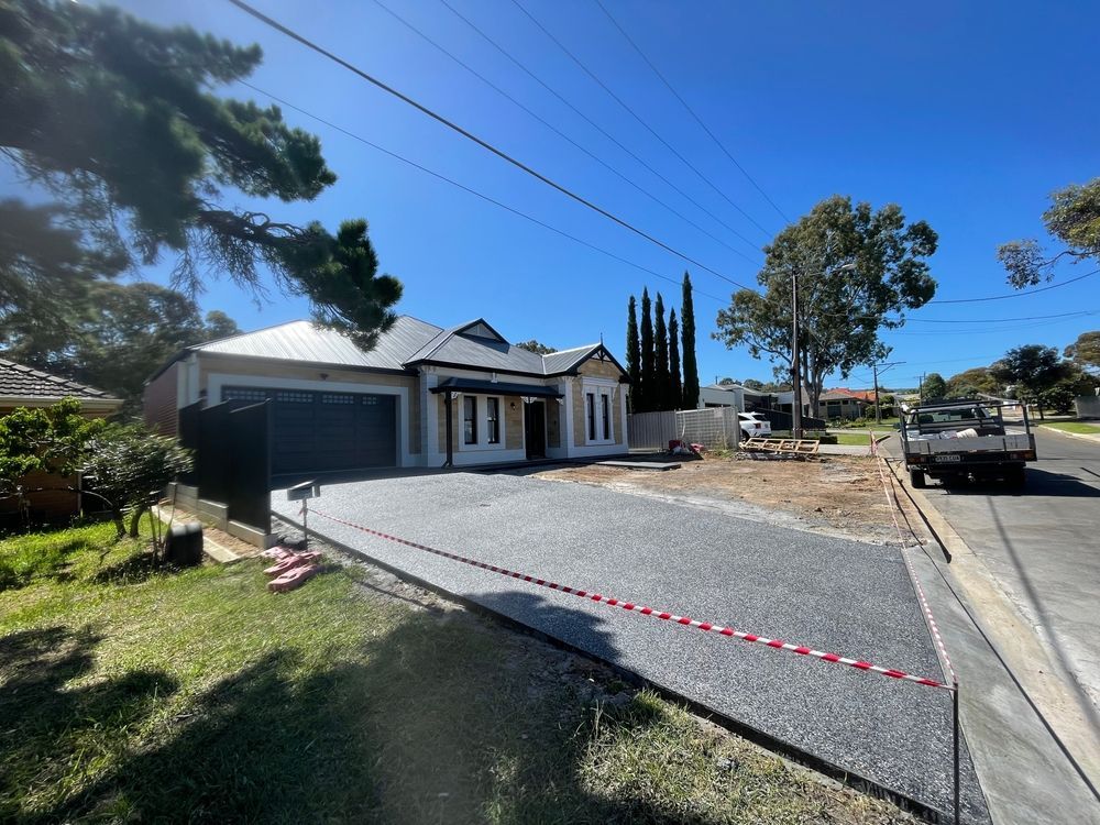 Newly paved driveway leading to a modern house on a sunny day.