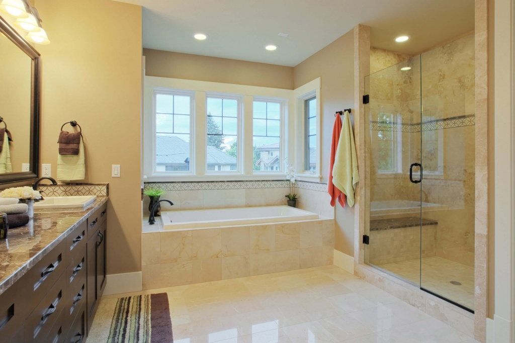 A bathroom with two sinks , a tub , and a walk in shower.