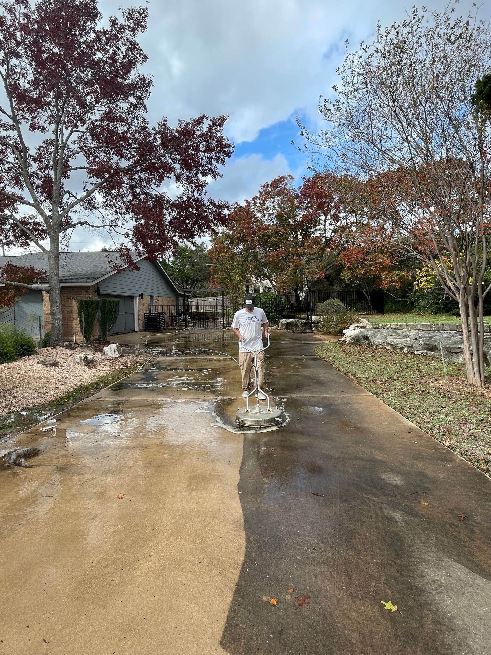 A man is walking down a wet driveway next to a house.