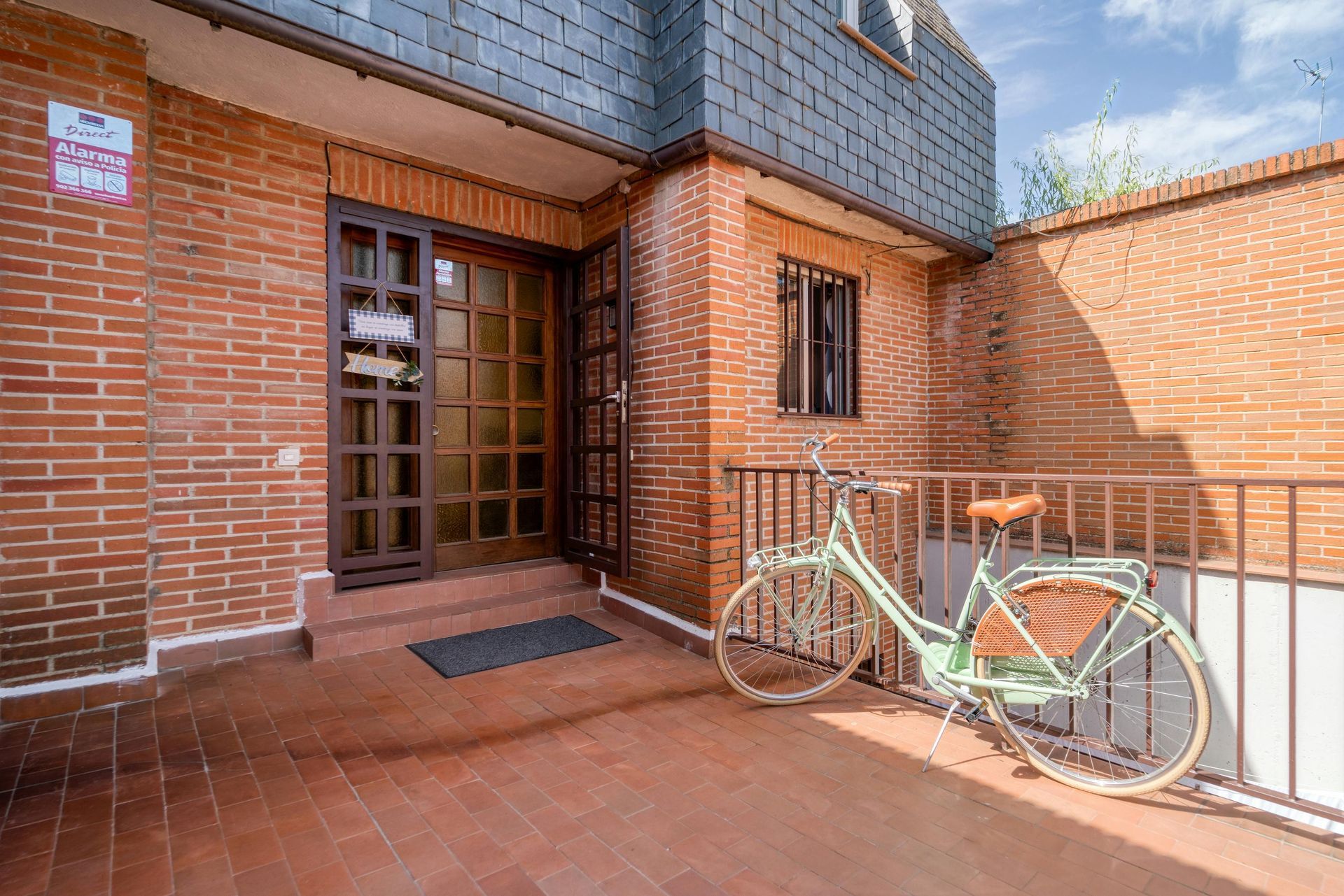 A green bicycle is parked in front of a brick building.