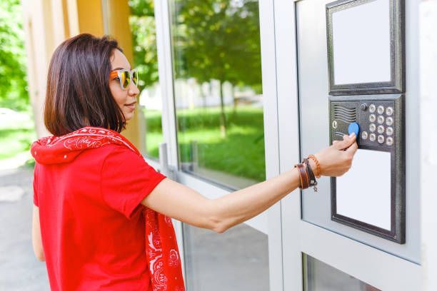 Woman using electronic key token for secure building entry. 
