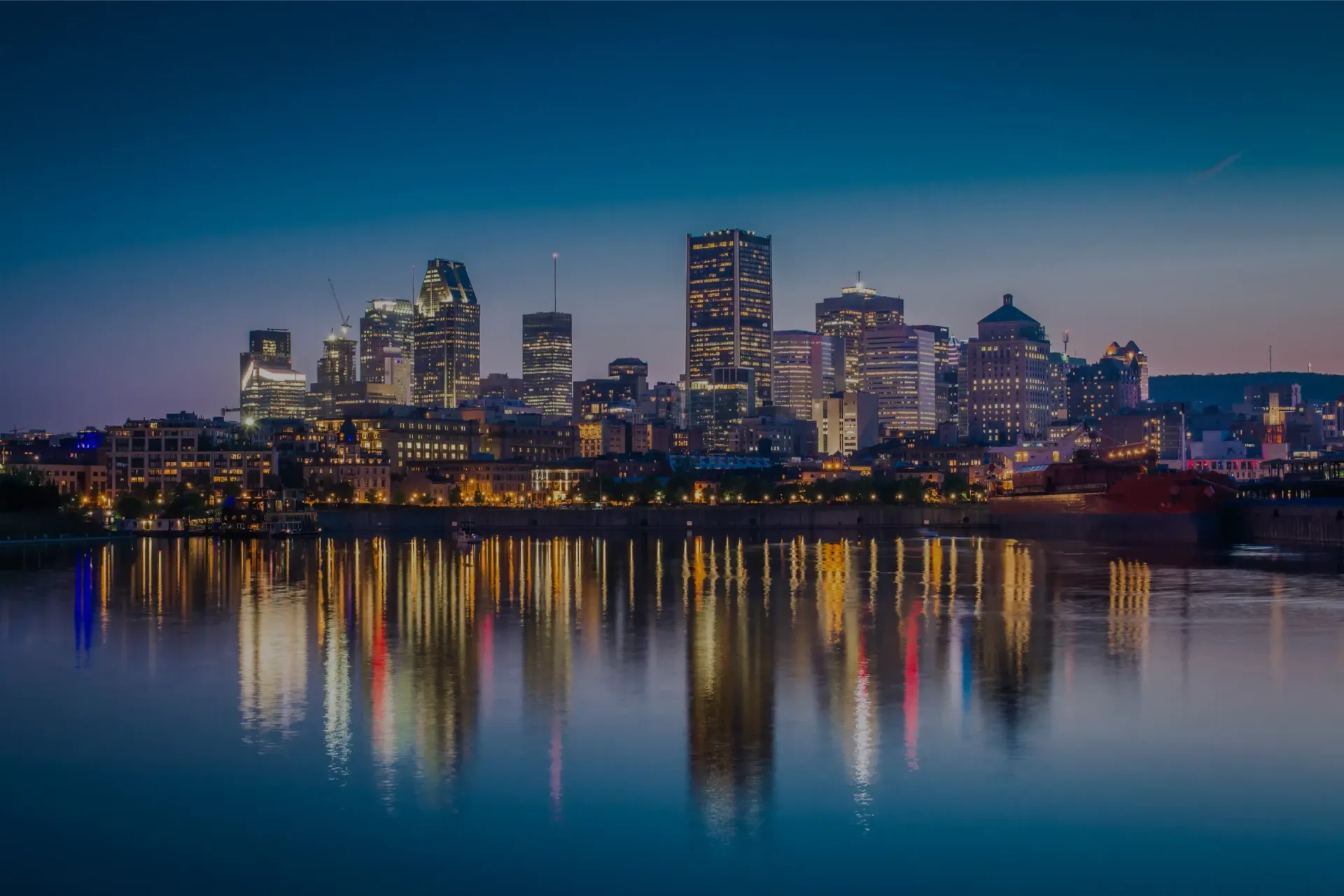 Montréal city skyline is reflected in a body of water at night.