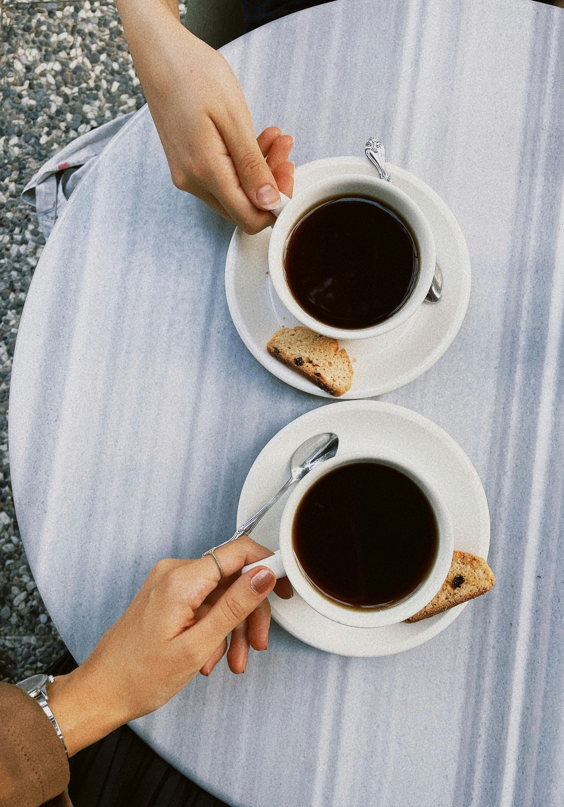 Two people are sitting at a table holding cups of coffee.