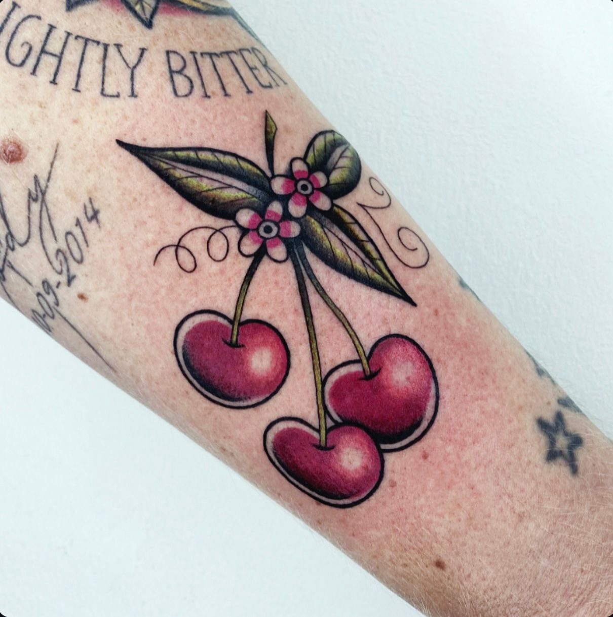Arm tattoo door Silke van Wijk, Sideways Tattoo Leeuwarden. Cherry, branches botanical color red green flowers traditional