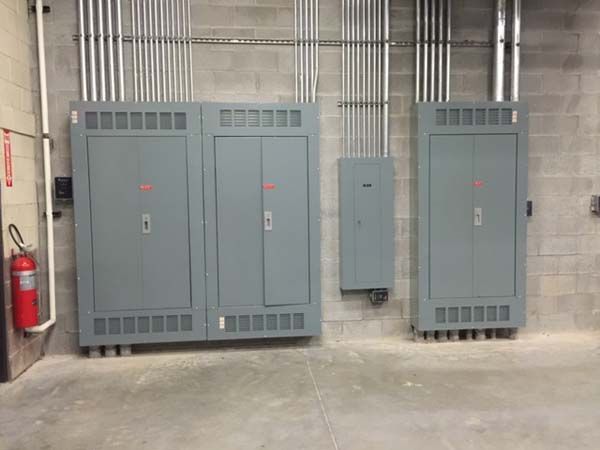 A room with three electrical boxes and a fire extinguisher.