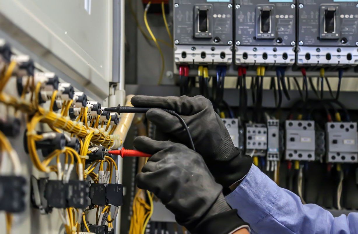 A man is working on an electrical panel with a screwdriver.