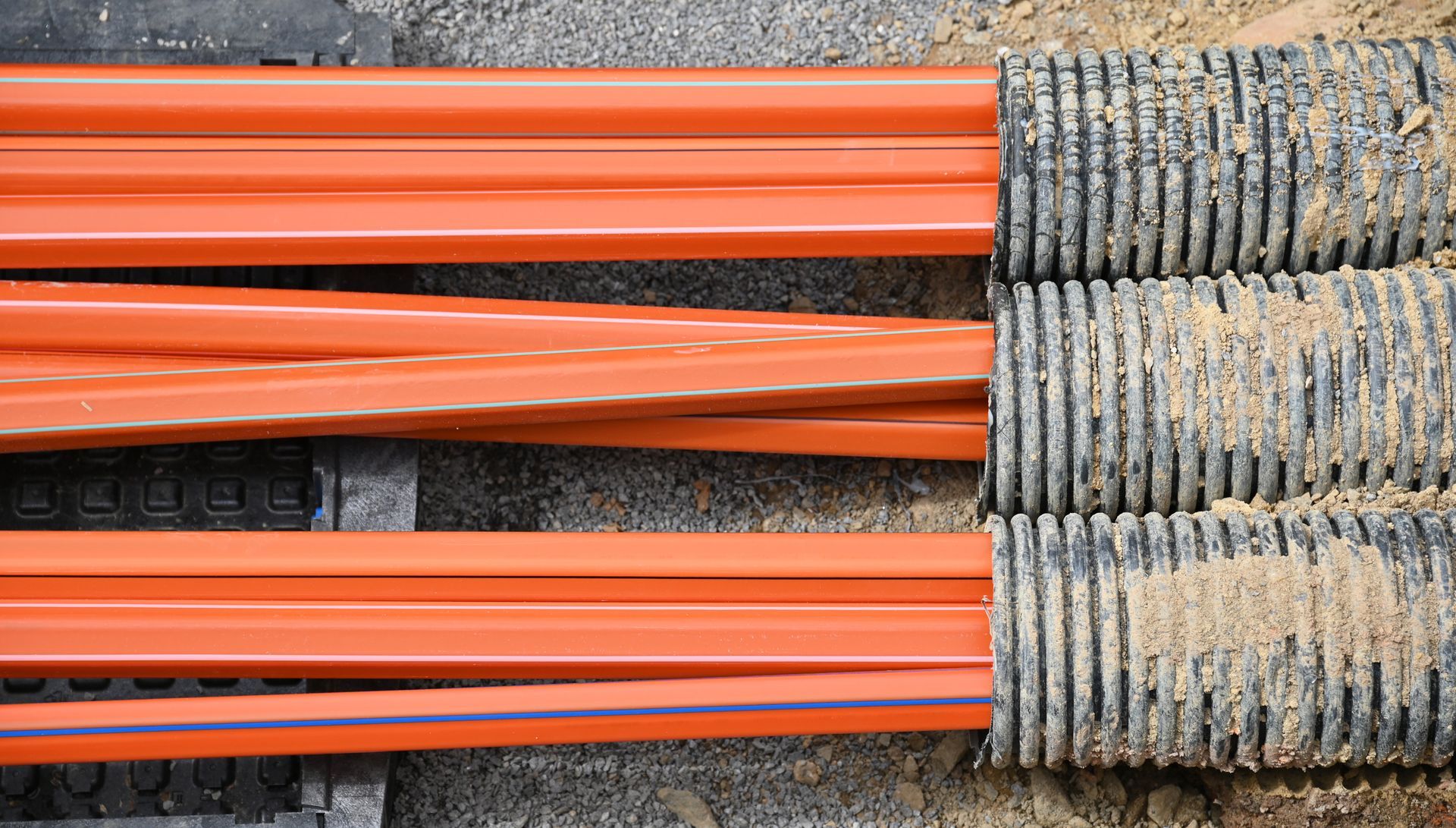 A bunch of orange pipes are laying on the ground.