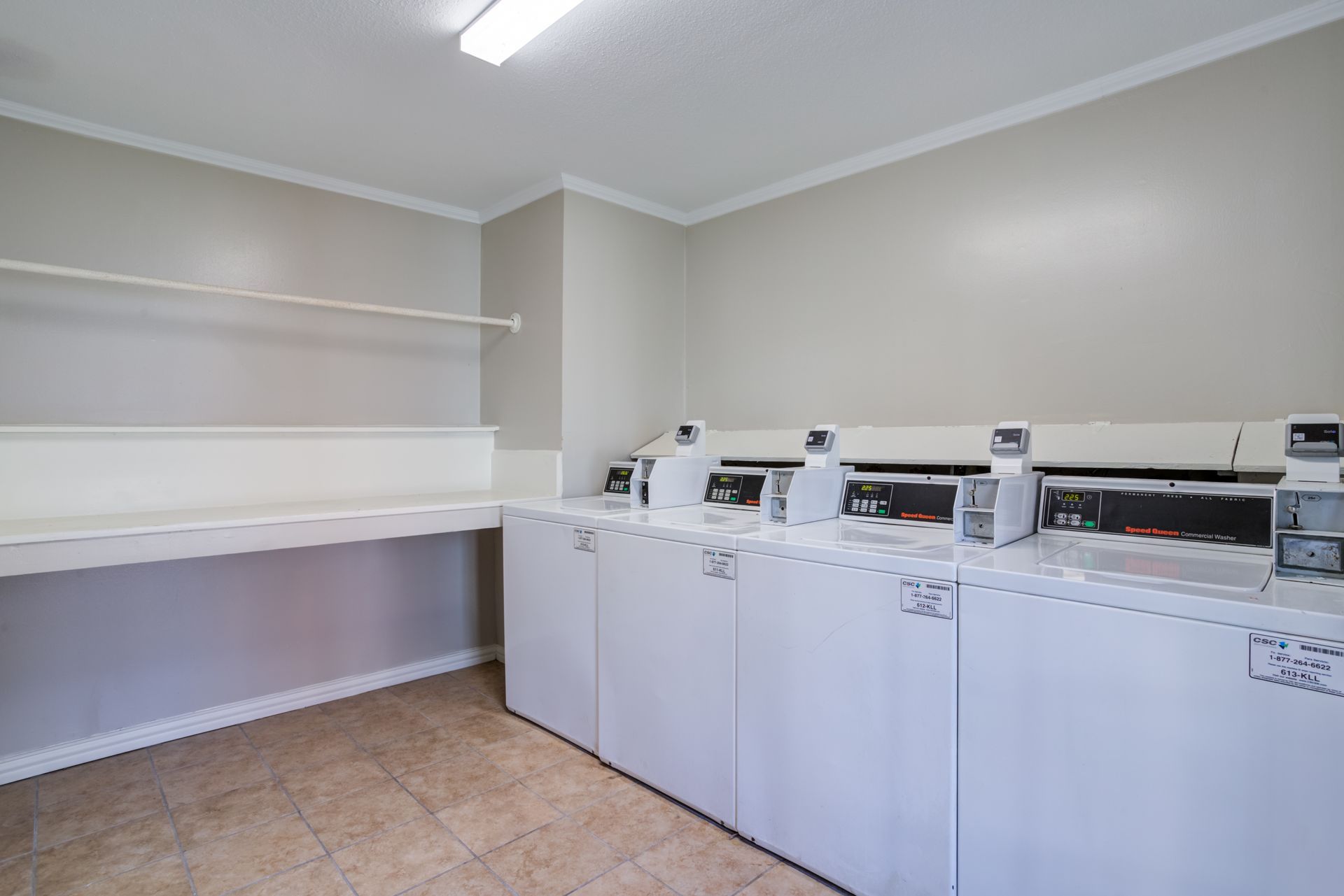 Laundry room with white appliances, countertop, and tan floor.