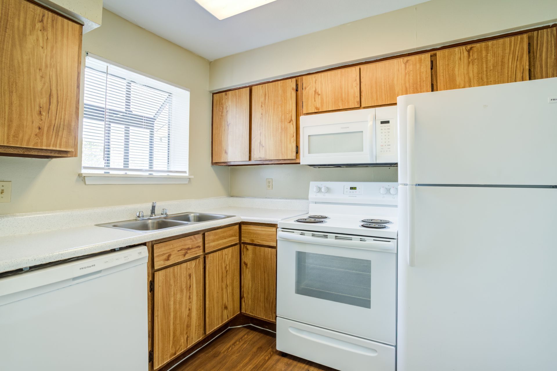 Kitchen with light wood cabinets, white appliances, and a window.