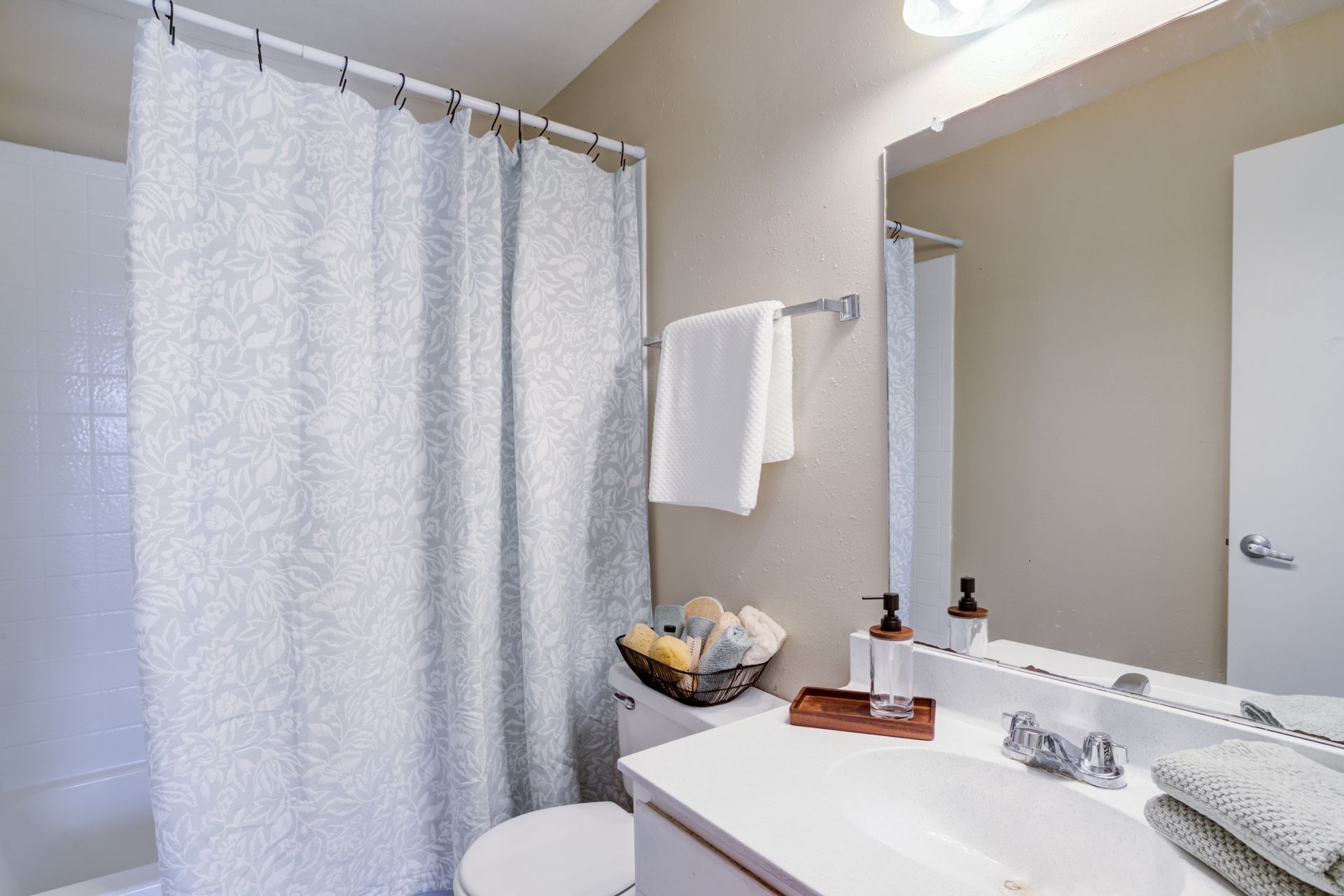 Bathroom with shower curtain, sink, mirror, and towel rack.