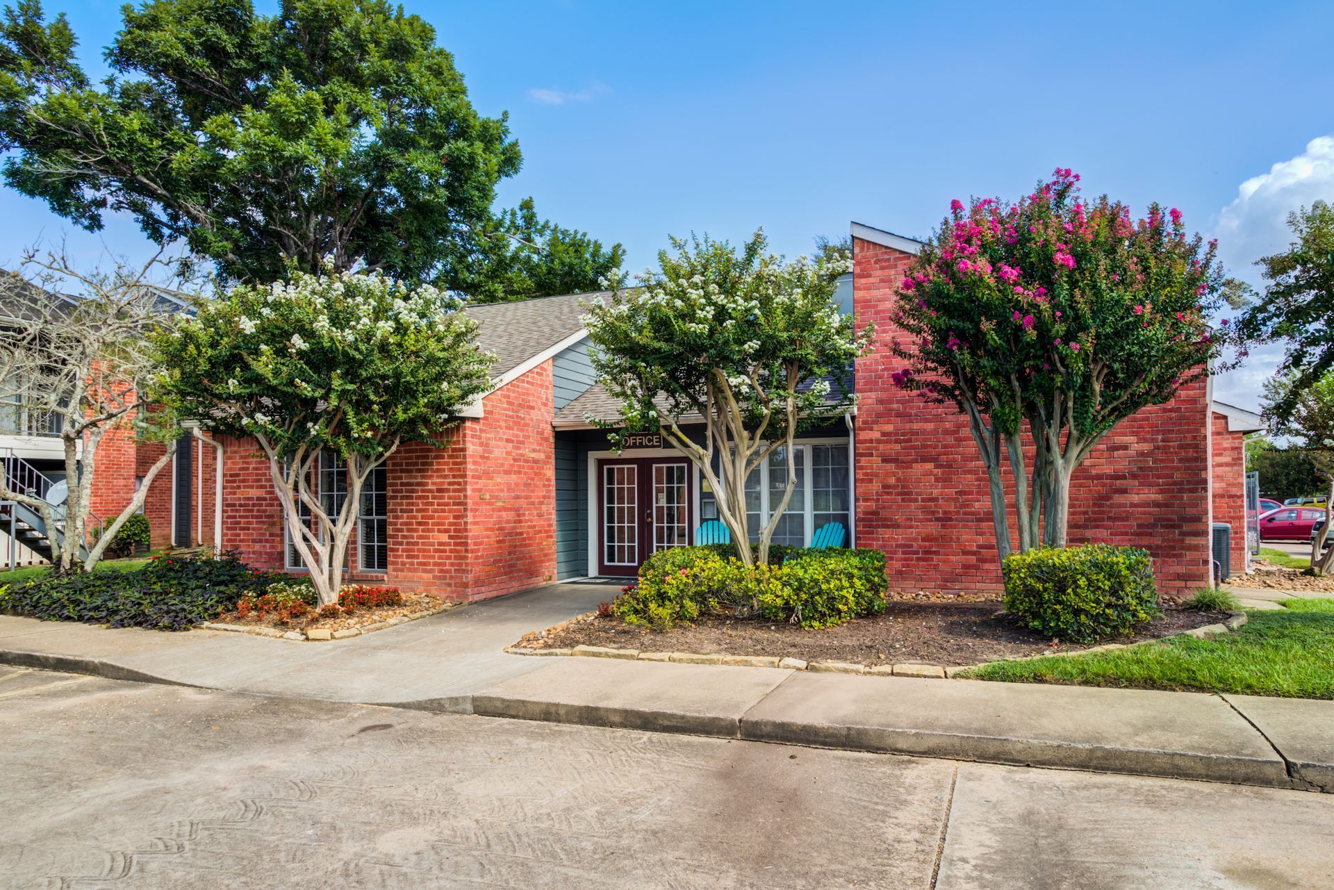 Red brick building with trees, blue sky, and a walkway.