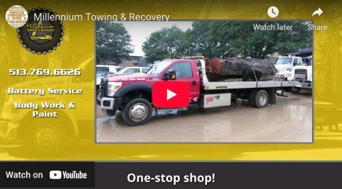 Red tow truck carrying debris; yellow background with text for Millennium Towing & Recovery, phone number, services, and a YouTube play button.