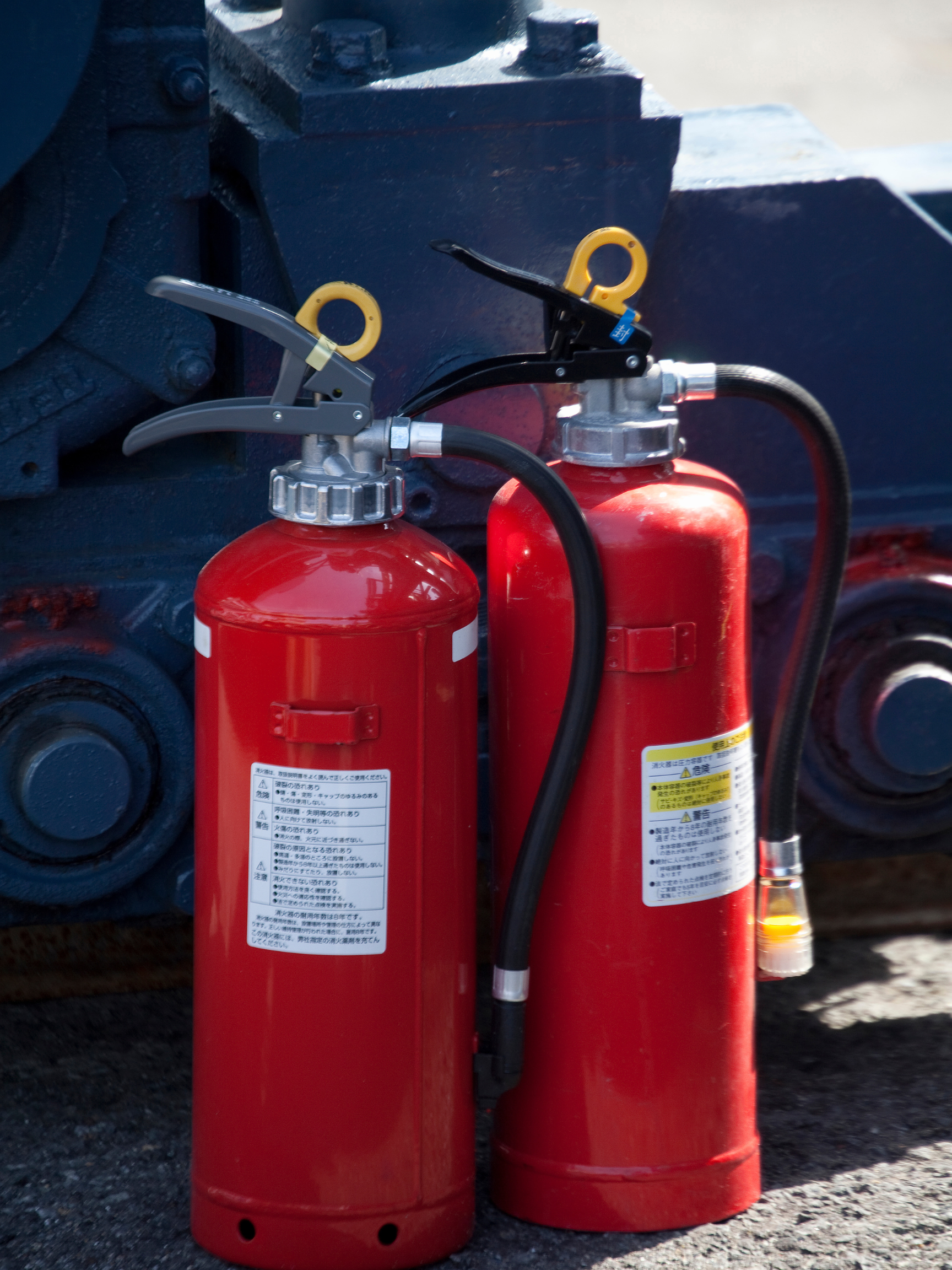two red fire extinguishers with foreign writing on them