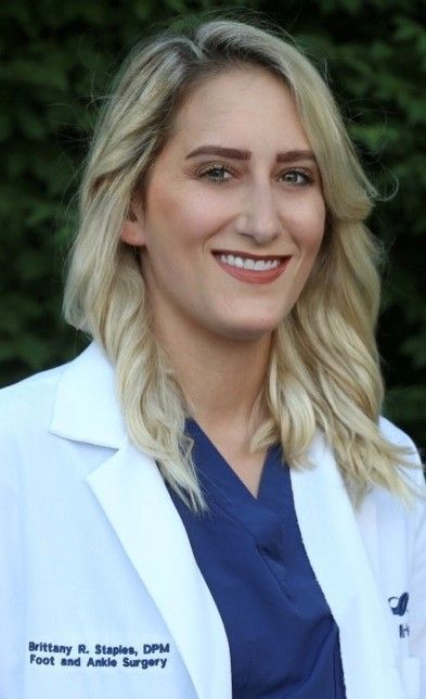 A smiling doctor in a lab coat with a stethoscope around his neck.