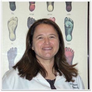 A smiling doctor in a lab coat with a stethoscope around his neck.