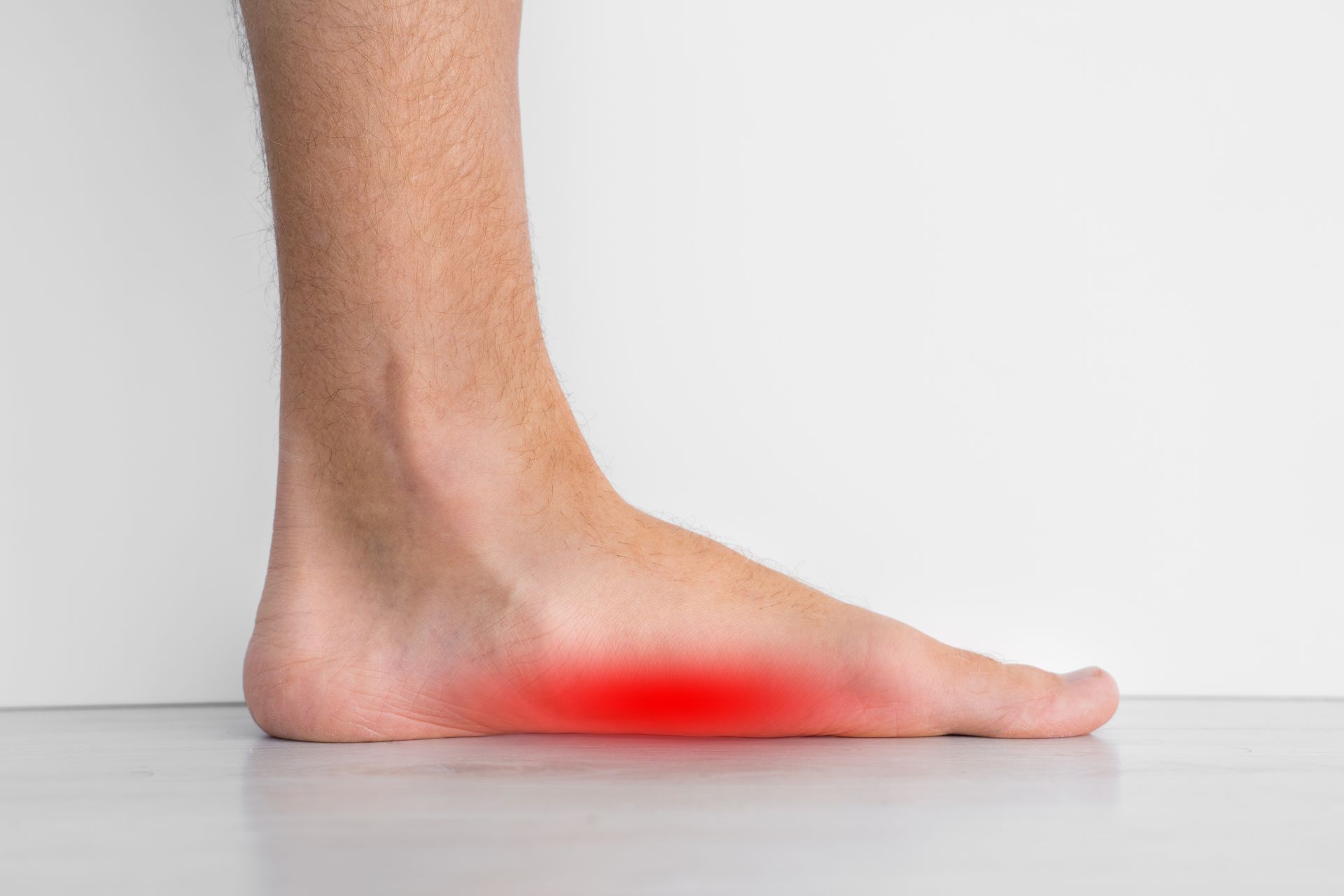 Foot with flat arch, highlighted red, indicating pain; indoors.