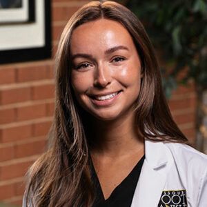 A smiling doctor in a lab coat with a stethoscope around his neck.